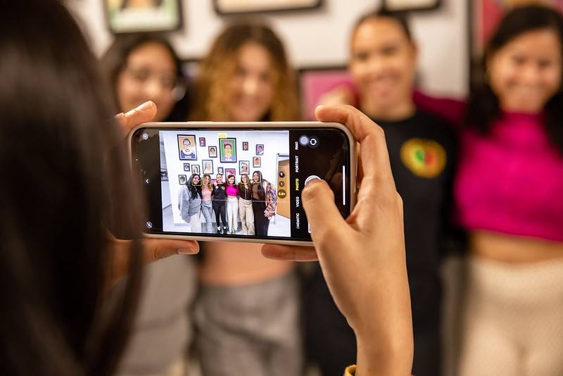 Girls taking a selfie in front of pictures of women at WGSC